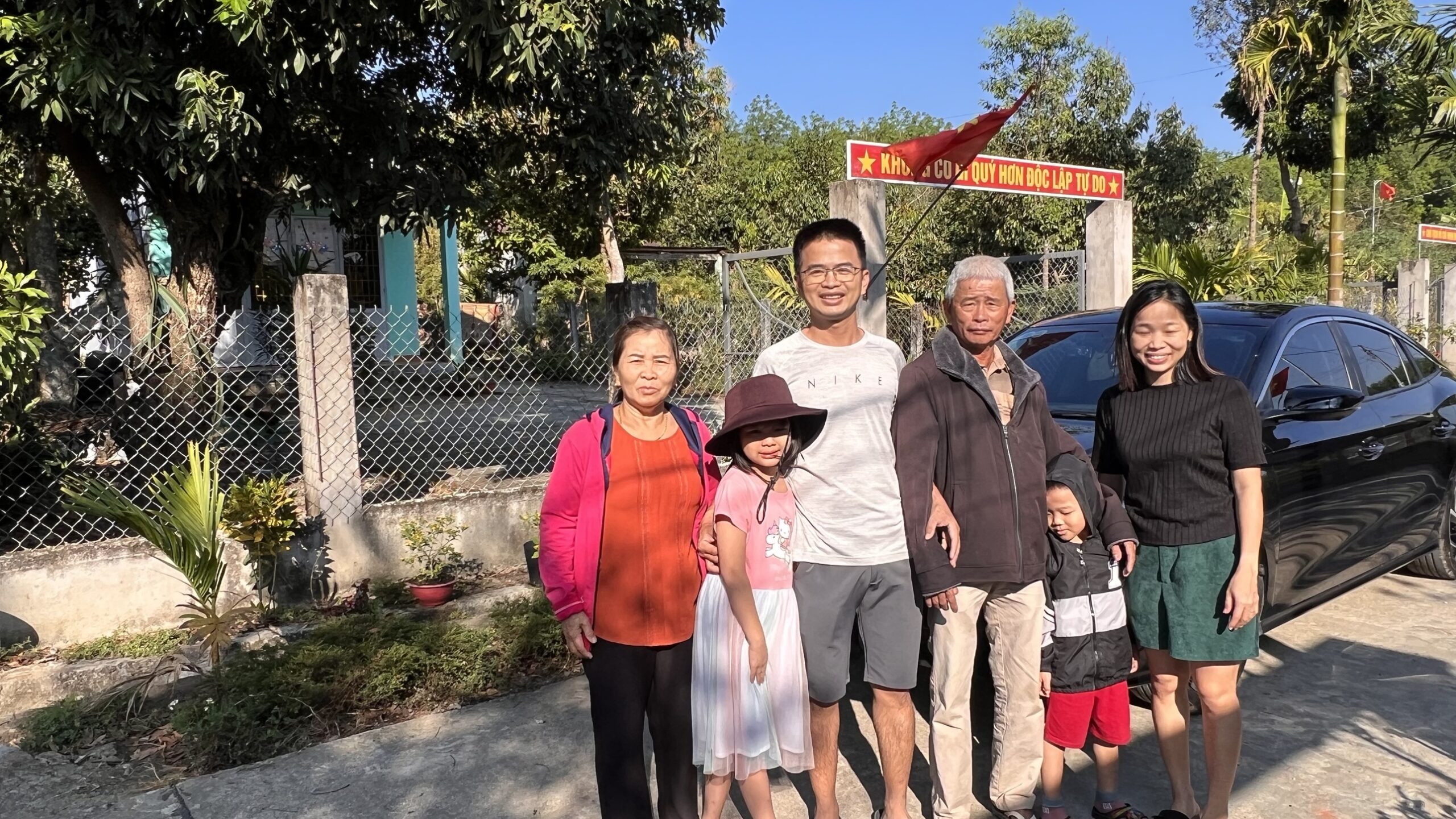 Cả nhà đứng chụp trước cổng nhà ở quê