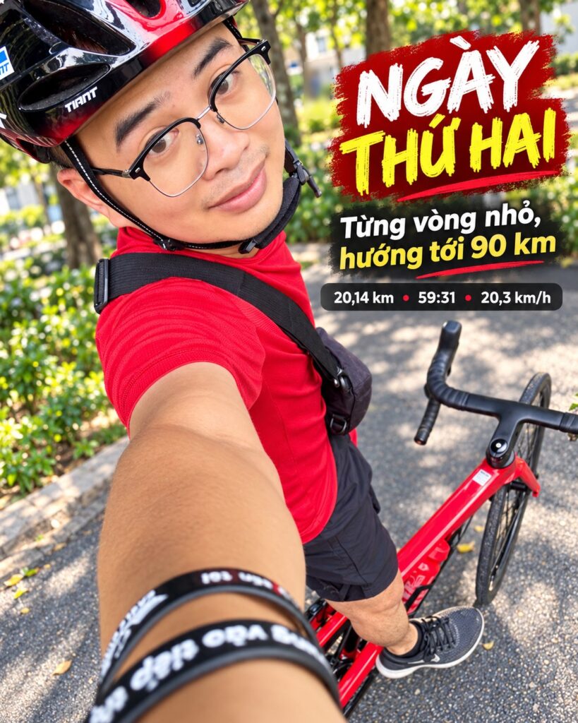 Lê Tấn Đào đội mũ bảo hiểm, mặc áo đỏ, chụp selfie bên chiếc xe đạp đường trường trong công viên ở buổi tập thứ hai